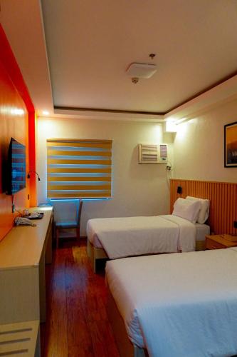 a hotel room with two beds and a desk at YMCA Makati in Manila