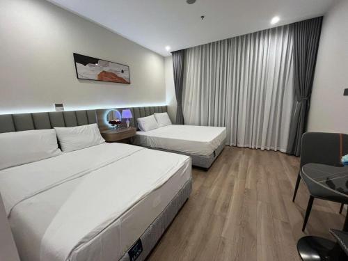 ein Hotelzimmer mit zwei Betten und einem Stuhl in der Unterkunft ICON40 HomeStay Hạ Long in Hạ Long