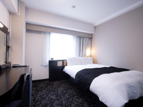 a hotel room with a bed and a desk and a window at APA Hotel Nagoya Sakae Ekimae EXCELLENT in Nagoya