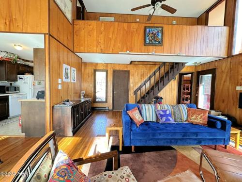 a living room with a blue couch and a kitchen at Paradise Uncovered Chalet Near Lake in Hawley