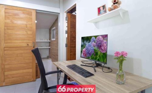 a desk with a computer and a vase of flowers at Nimman Home with Cozy Patio - Workspace w Screen in Chiang Mai