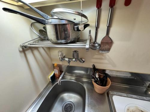a kitchen sink with a pot and utensils on a shelf at 京橋プルトンビル in Osaka