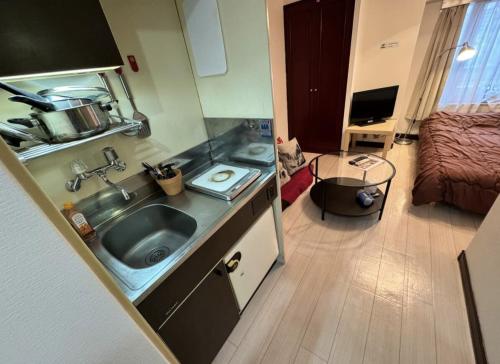 a small kitchen with a sink and a bedroom at 京橋プルトンビル in Osaka