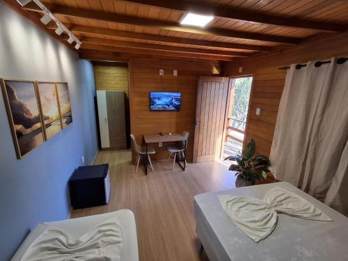 a room with two beds and a dining room with a table at Pousada Laranjal em Pelotas in Pelotas