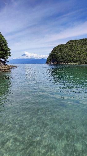 a large body of water with a mountain in the background at 貸切宿 ひととき -Hitotoki- 眺めの良いテラスでBBQが楽しめる 徒歩で海と温泉へ 温泉券プレゼント 最大12名 in Numazu