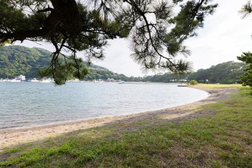 a view of a beach with trees and the water at 貸切宿 ひととき -Hitotoki- 眺めの良いテラスでBBQが楽しめる 徒歩で海と温泉へ 温泉券プレゼント 最大12名 in Numazu