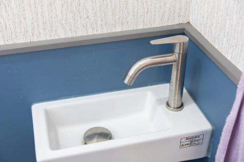 a white sink in a bathroom with a blue wall at 貸切宿 ひととき -Hitotoki- 眺めの良いテラスでBBQが楽しめる 徒歩で海と温泉へ 温泉券プレゼント 最大12名 in Numazu