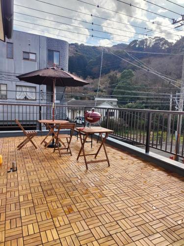 a patio with a table and an umbrella on a balcony at 貸切宿 ひととき -Hitotoki- 眺めの良いテラスでBBQが楽しめる 徒歩で海と温泉へ 温泉券プレゼント 最大12名 in Numazu