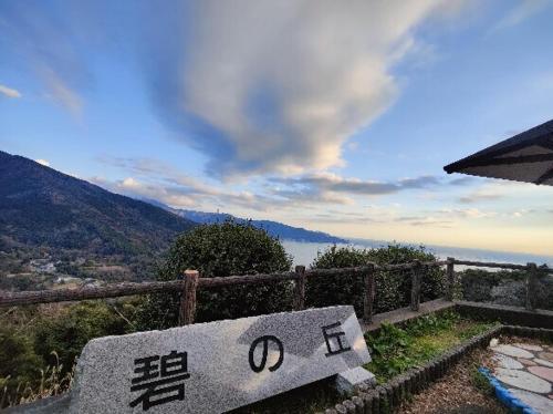 a stone bench with writing on it in front of a mountain at 貸切宿 ひととき -Hitotoki- 眺めの良いテラスでBBQが楽しめる 徒歩で海と温泉へ 温泉券プレゼント 最大12名 in Numazu