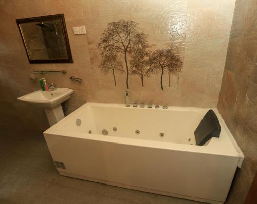une baignoire blanche dans une salle de bain avec un lavabo dans l'établissement King's Court Kandy, à Kandy