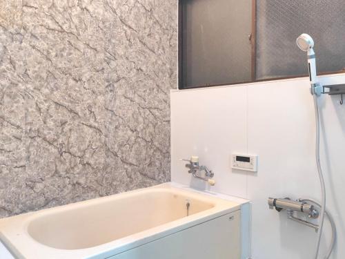 a bathroom with a sink and a bath tub at 貸切宿 ひととき -Hitotoki- 眺めの良いテラスでBBQが楽しめる 徒歩で海と温泉へ 温泉券プレゼント 最大12名 in Numazu