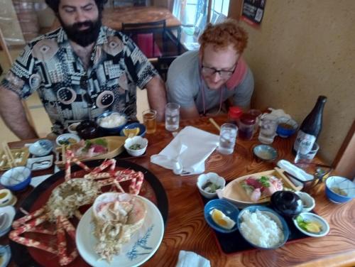 two men sitting at a table with food on it at 貸切宿 ひととき -Hitotoki- 眺めの良いテラスでBBQが楽しめる 徒歩で海と温泉へ 温泉券プレゼント 最大12名 in Numazu