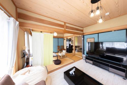 a living room with a large flat screen tv at 貸切宿 ひととき -Hitotoki- 眺めの良いテラスでBBQが楽しめる 徒歩で海と温泉へ 温泉券プレゼント 最大12名 in Numazu