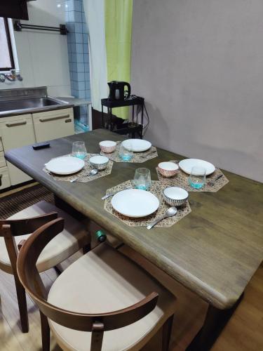 a table with plates and glasses on it in a kitchen at 貸切宿 ひととき -Hitotoki- 眺めの良いテラスでBBQが楽しめる 徒歩で海と温泉へ 温泉券プレゼント 最大12名 in Numazu