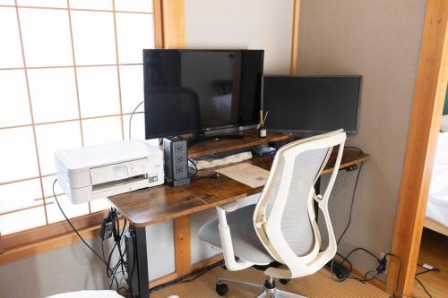 a desk with a computer and a monitor and a computer chair at 貸切宿 ひととき -Hitotoki- 眺めの良いテラスでBBQが楽しめる 徒歩で海と温泉へ 温泉券プレゼント 最大12名 in Numazu