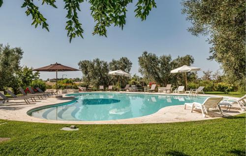 a swimming pool with chairs and umbrellas in a yard at Nice Home In Montalto Di Castro in Montalto di Castro