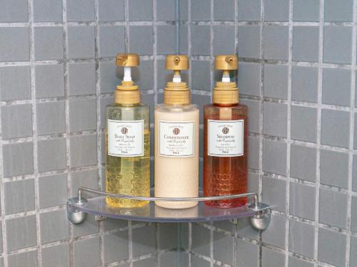 three bottles of essential oils on a shelf in a bathroom at Sutton Hotel Hakata City in Fukuoka