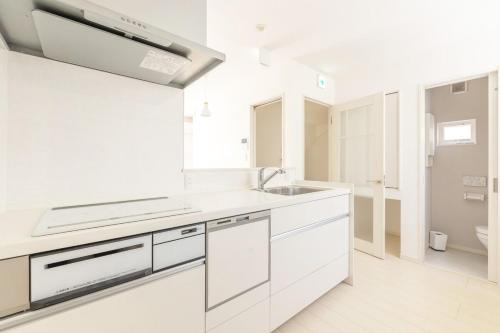 a white kitchen with white cabinets and a sink at Near Shinjuku 3 stops in Tokyo