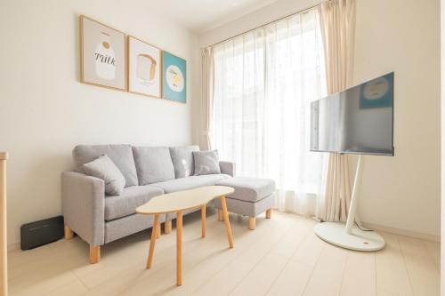 a living room with a couch and a table and a tv at Near Shinjuku 3 stops in Tokyo