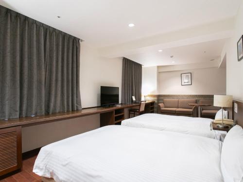 a hotel room with two beds and a couch at Sutton Hotel Hakata City in Fukuoka