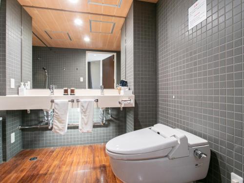 a bathroom with a toilet and a sink and a mirror at Sutton Hotel Hakata City in Fukuoka