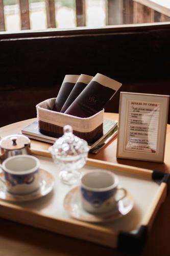 a tray with two cups and a box on a table at Chale com hidro na Serra da Mantiqueira in Sapucaí-Mirim