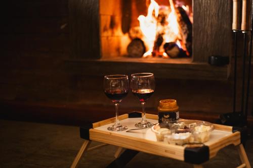 two glasses of wine on a table in front of a fireplace at Chale com hidro na Serra da Mantiqueira in Sapucaí-Mirim