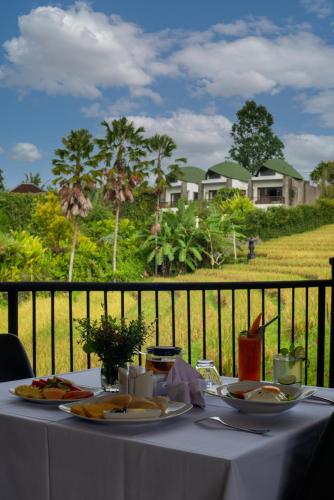 un tavolo bianco con piatti di cibo su un balcone di De Moksha Eco Friendly Boutique Resort a Tanah Lot