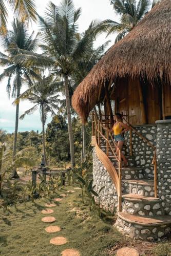 a woman standing on the stairs of a hut at La Royale Nusa Penida in Nusa Penida