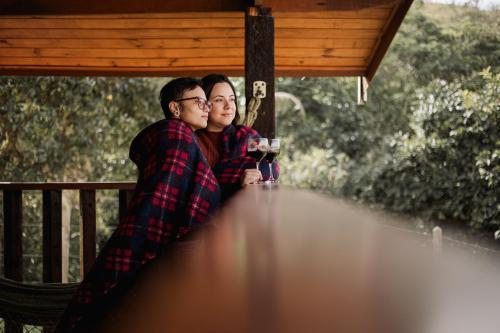 a man and a woman sitting on a table on a porch at Chale com hidro na Serra da Mantiqueira in Sapucaí-Mirim