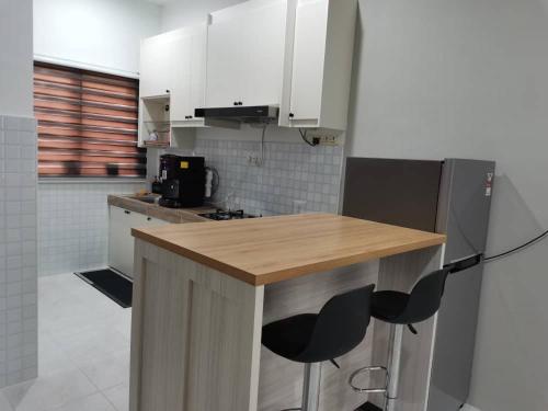 a kitchen with a wooden counter and two bar stools at Maldira Homestay in Batu Gajah in Gua Sai