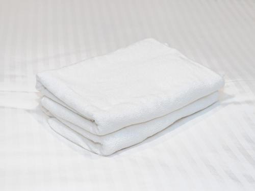 a stack of white towels sitting on a bed at Sutton Hotel Hakata City in Fukuoka