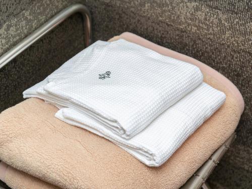 a pile of white towels sitting on a chair at Sutton Hotel Hakata City in Fukuoka