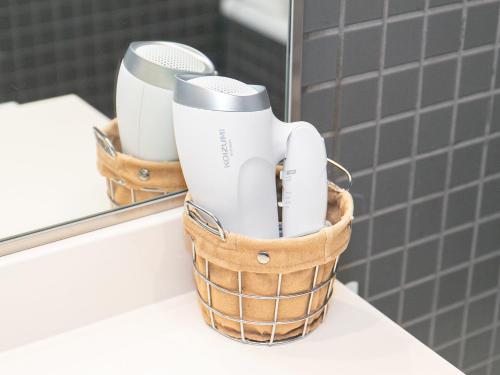 a basket of toothbrushes on a counter in front of a mirror at Sutton Hotel Hakata City in Fukuoka