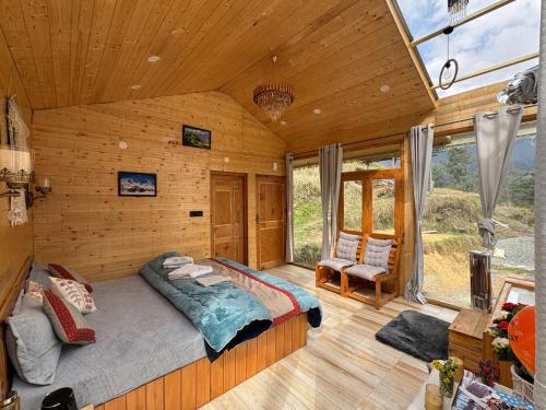 una camera da letto con un grande letto in una camera in legno di SkyHeaven Jacuzzi Treehouse a Jibhi