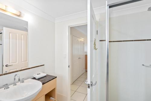 a white bathroom with a sink and a shower at Cairns City Apartments in Cairns