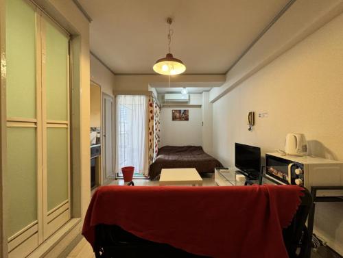 a room with a bed and a desk with a red blanket at 京橋プルトンビル in Osaka