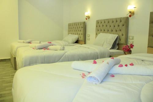 a hotel room with three beds with pink flowers on them at khufus pyramids hotel in Cairo