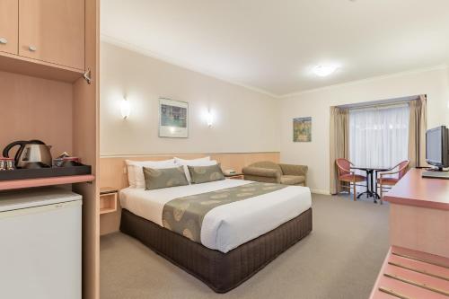 a hotel room with a bed and a kitchen at The Waverley International Hotel in Glen Waverley