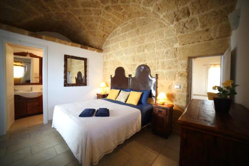 a bedroom with a bed and a bathroom with a sink at La Corte Delle Sterne in Morciano di Leuca