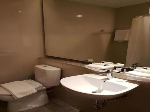 a bathroom with a sink and a toilet and a mirror at Wing Hotel Kualanamu Airport in Medan