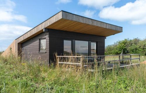a black house on top of a grassy hill at Cozy Home In Sejerø With Wifi in Sejerby