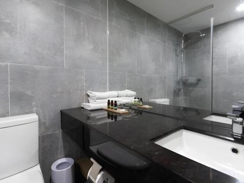 a bathroom with a sink and a toilet and a tub at Ebenezer Hotel in Jeju