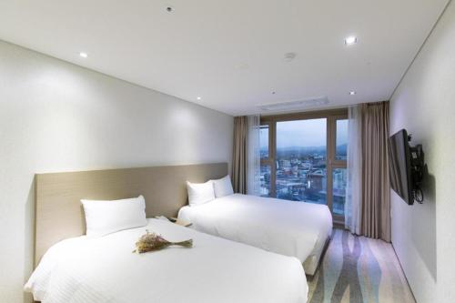 a hotel room with two beds and a window at Ebenezer Hotel in Jeju