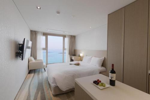 a hotel room with a bed and a table with a bottle of wine at Ebenezer Hotel in Jeju