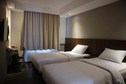 茂物Bianco Costel的有两张床和一扇窗户的酒店房间