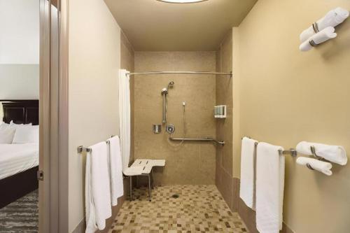 a bathroom with a shower and a bed and towels at Best Western Frontier Motel in Lone Pine
