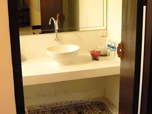 une salle de bain avec un lavabo blanc et un miroir dans l'établissement Montrara Happy House Hotel, à Chiang Mai