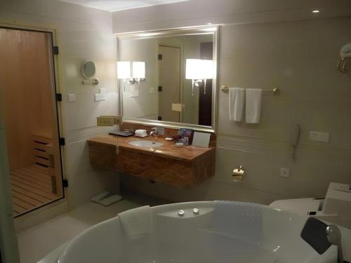 a bathroom with a tub and a sink and a mirror at Fujian Galaxy Garden Hotel in Fuzhou