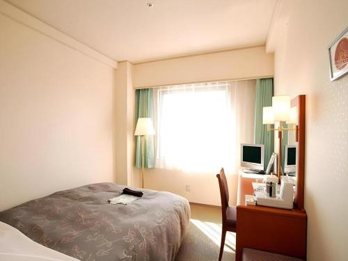 a hotel room with a bed and a desk and a window at Hotel Royal Hill Fukuchiyama and Spa in Fukuchiyama